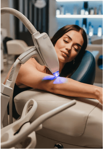 Woman receiving laser treatment on arm in a spa setting.